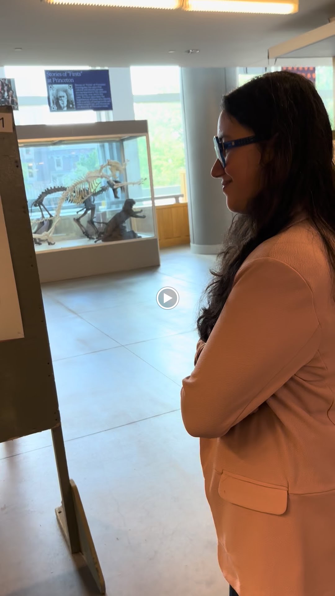 Shalvi looking at a mounted fossil skeleton inside a glass display case.